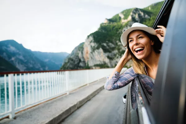 Road trip by car - experience unforgettable adventures woman in car road trip waving out the window smili 2022 01 18 23 40 11 utc 600x400 - Road trip by car - Experience unforgettable adventures